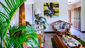 A living room with a sofa, armchairs, a lamp, and a painting on the wall. - Lotfa Resort Diani (Diani Beach)