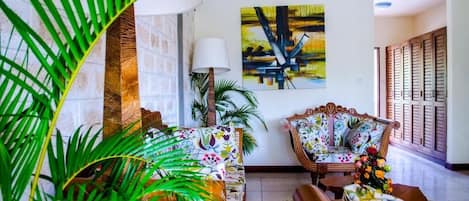 Una sala de estar con sofá, sillones, una lámpara y un cuadro en la pared.