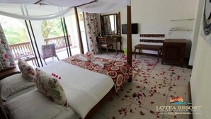 A room with a bed, a desk, and a chair, with a balcony visible through the window. - Lotfa Resort Diani (Diani Beach)