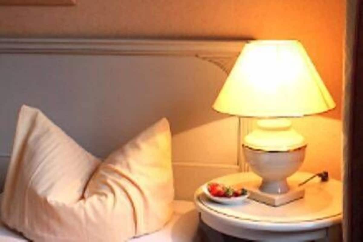 Habitación de hotel con cama, mesita de noche con lámpara y un frutero pequeño.