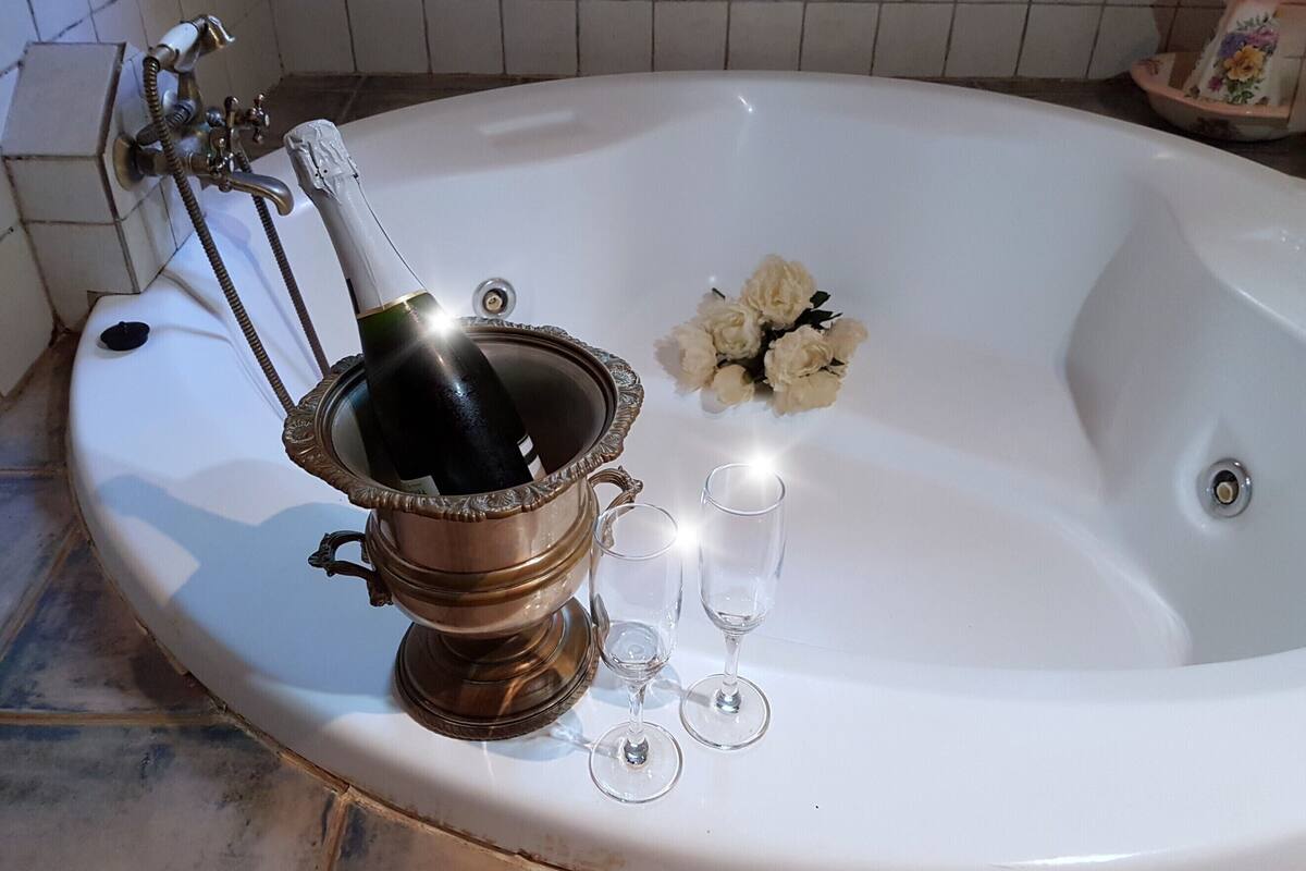 A bathtub with a bottle of champagne, two wine glasses, and a bouquet of flowers.