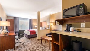A hotel room with a bed, desk, chair, microwave, coffee maker, and a trash bin. - Comfort Inn & Suites (Clarington)