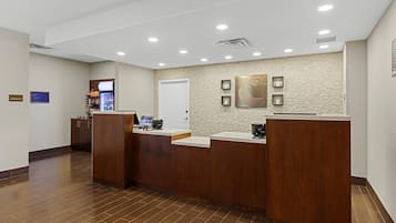 Zona de recepción con mostrador de madera, un reloj en la pared y máquina expendedora.