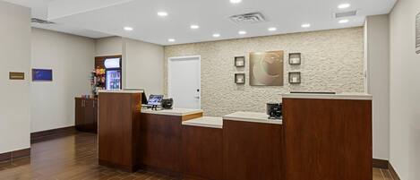 A reception area with a wooden reception desk, a wall-mounted clock, and a vending machine.