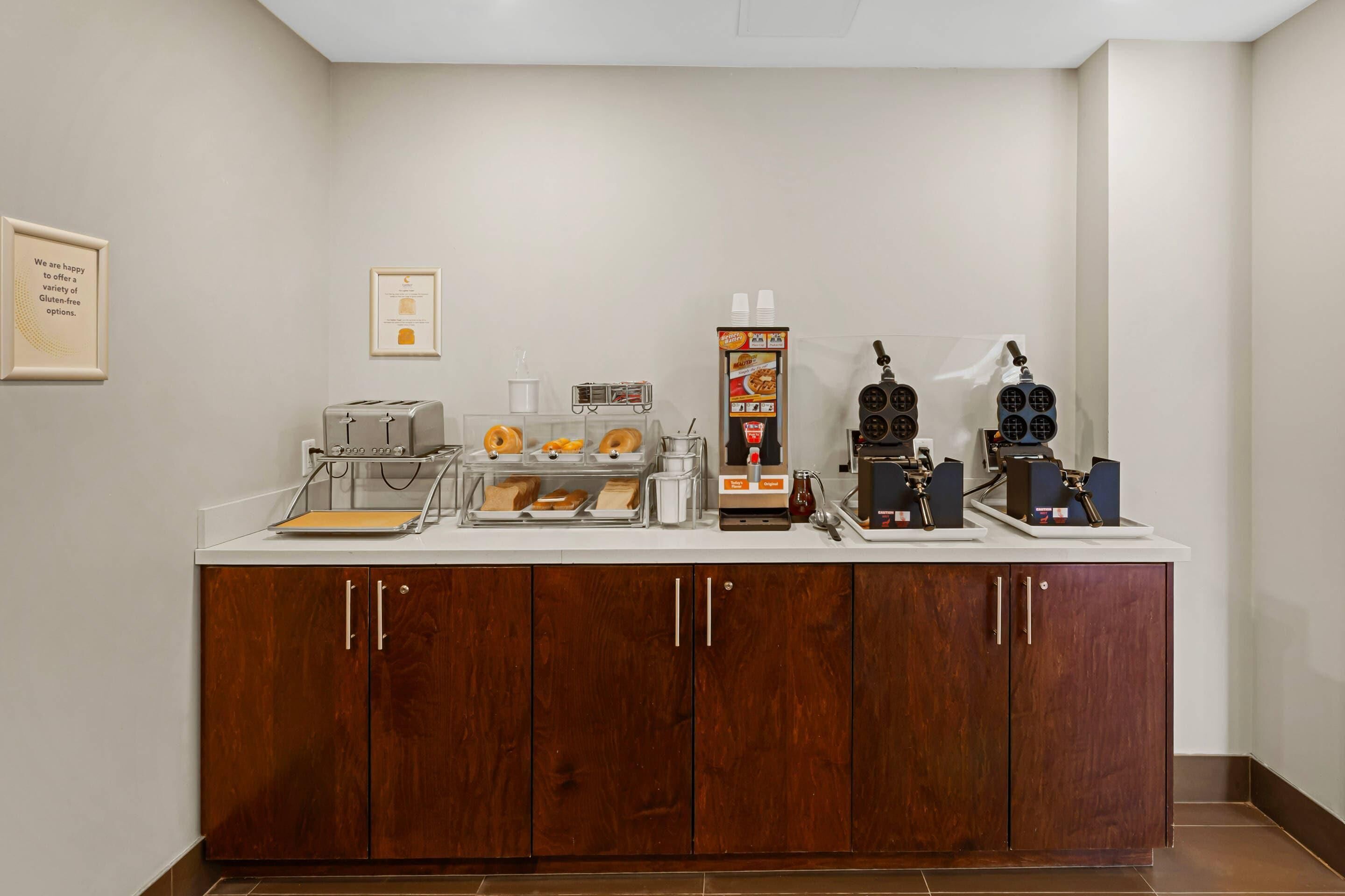 Una barra de desayuno con cafetera, tostadora y exhibición de alimentos.