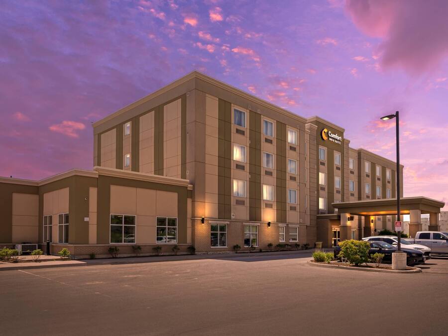 Een groot hotel met modern design, meerdere verdiepingen en een parkeerplaats.
