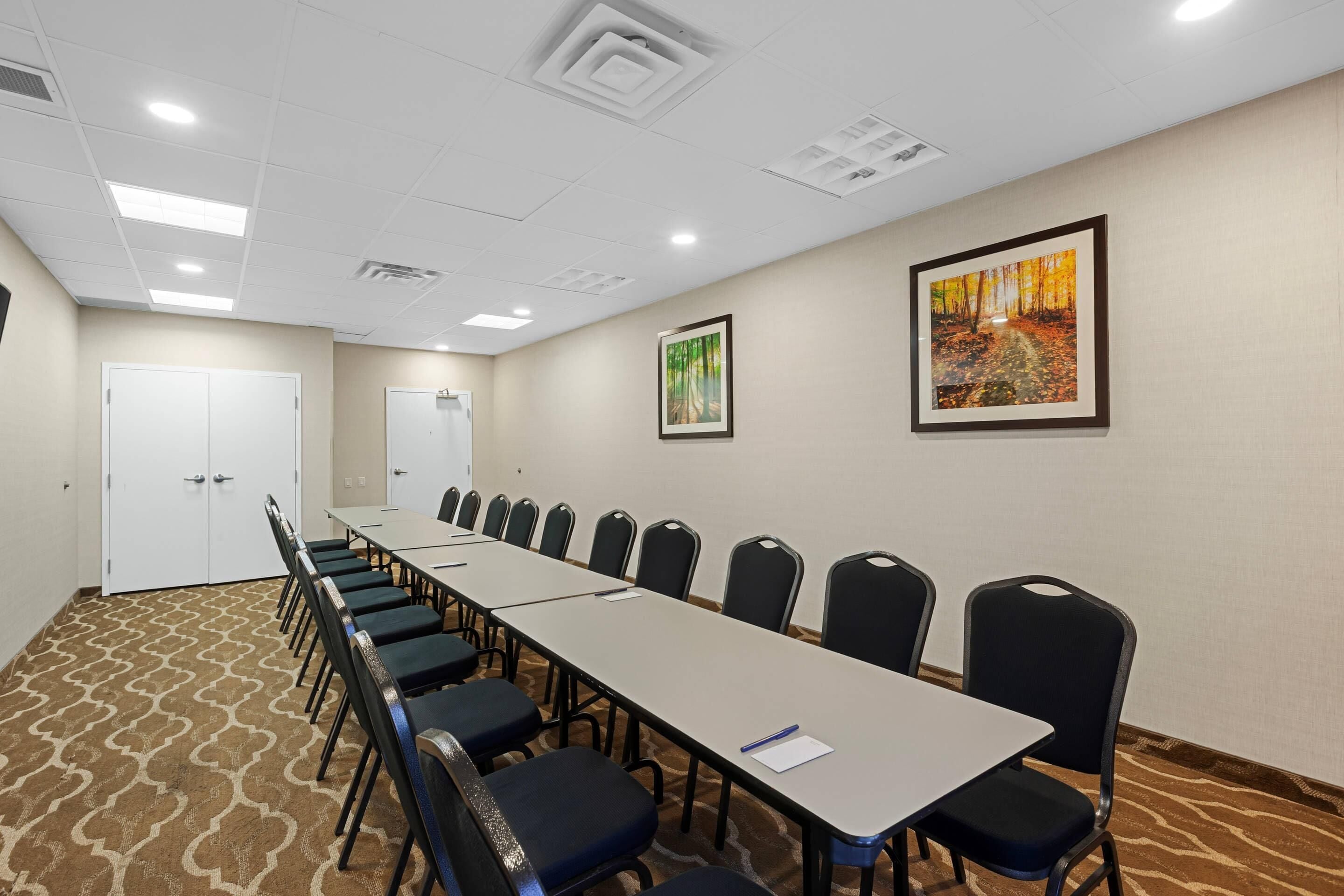 Un salón de conferencias con una larga mesa, sillas y dos puertas.