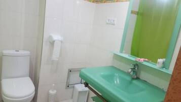 A bathroom with a white toilet, a green sink, and a mirror with a green frame.