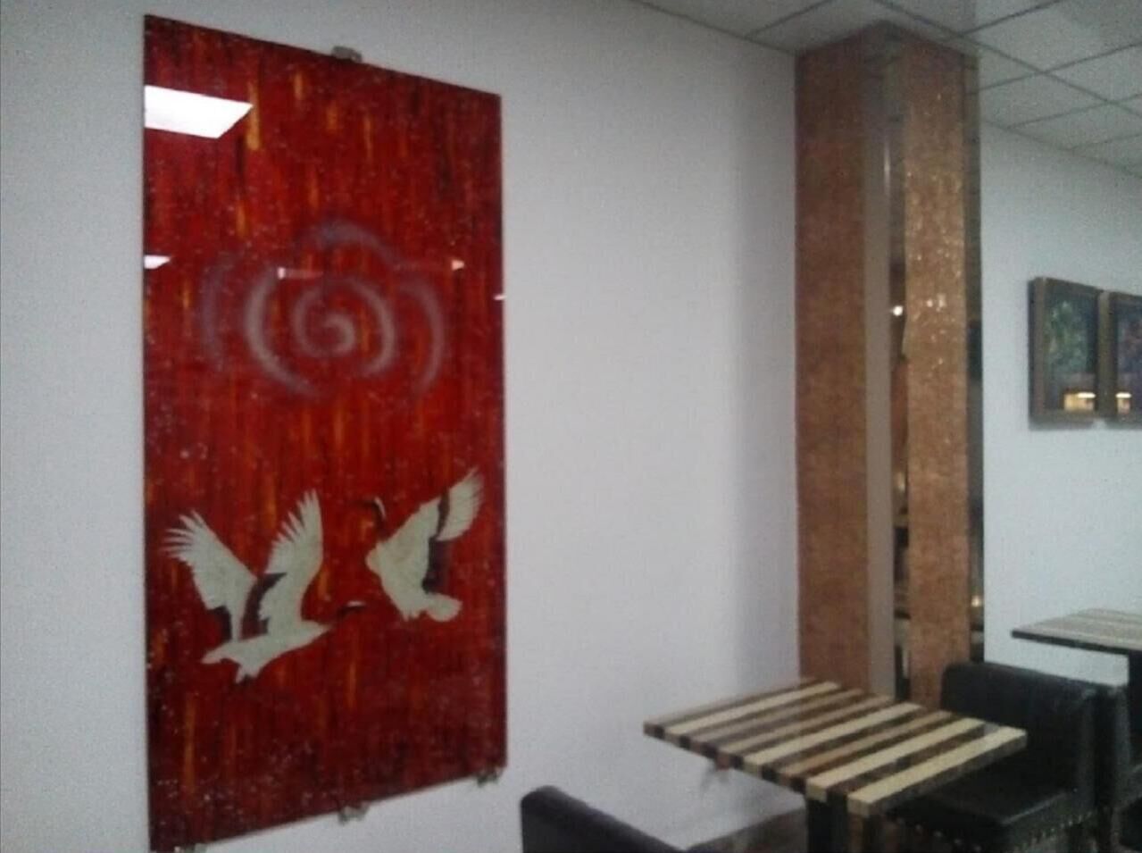 A room with a red abstract wall art, a wooden bench, and a pillar.