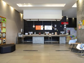 Uma área de recepção moderna com balcão, computadores e a placa 'Check-in'.