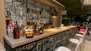 Un espace bar avec un comptoir, différentes bouteilles, un distributeur automatique et une fresque murale.