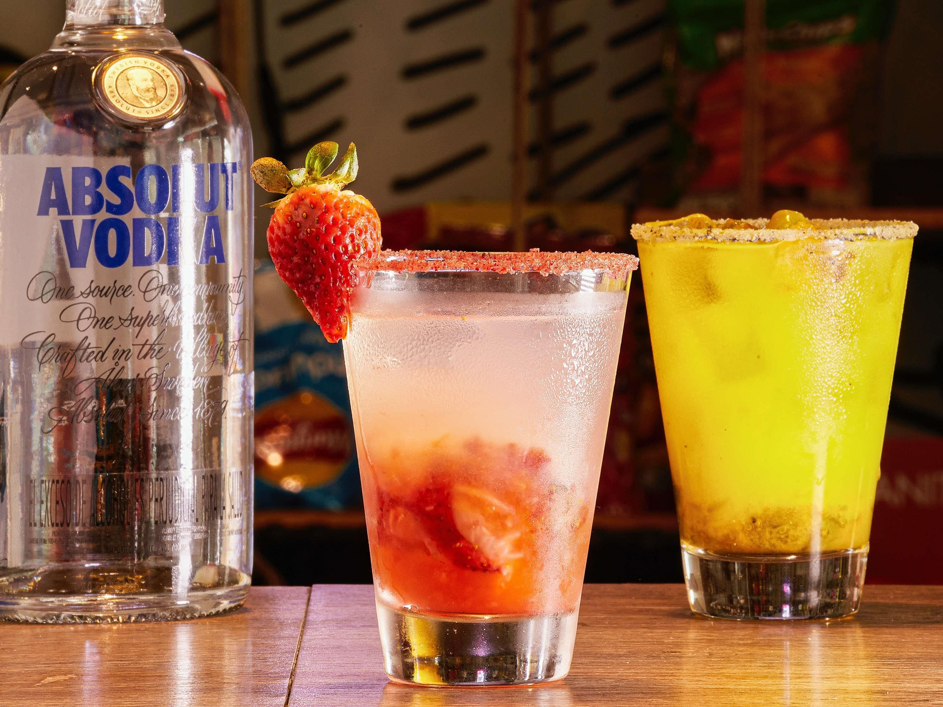 Trois verres de cocktails variés, accompagnés d’une bouteille de vodka Absolut.