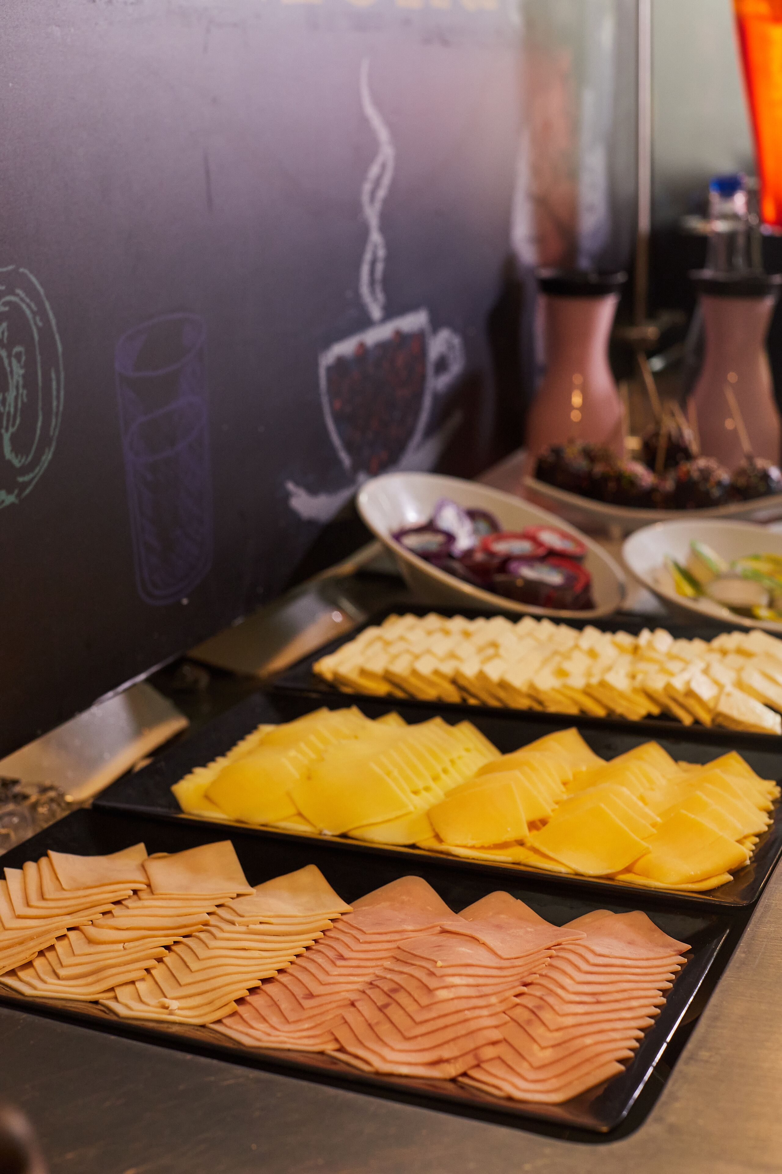 Buffet com diversos alimentos, incluindo fatias de carnes e queijos.