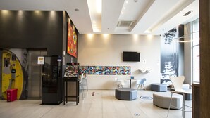 Un hall d’entrée moderne doté d’un distributeur automatique, d’un espace salon et d’une œuvre d’art murale aux couleurs vives.