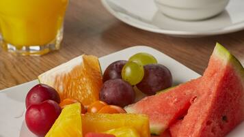 Un plato de fruta y una taza de café sobre una mesa de madera.