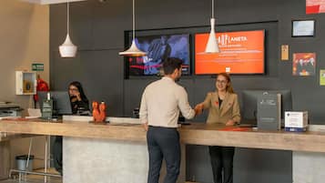 A reception desk with a digital screen displaying a video, a sign for a check-out express service, and a framed artwork on the wall.