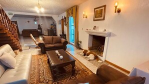 Una sala acogedora con chimenea, una escalera y un comedor.