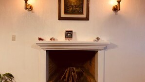 Una chimenea con una obra de arte enmarcada encima, un letrero sobre la repisa y apliques de pared.