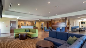 A spacious lobby with a reception desk, sofas, and a coffee machine. - Comfort Inn & Suites – Harrisburg Airport – Hershey South (Middletown)