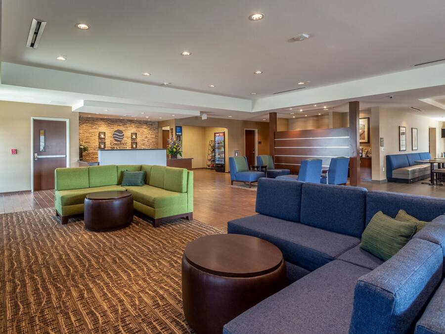 A spacious lobby with a reception desk, sofas, and a coffee machine.