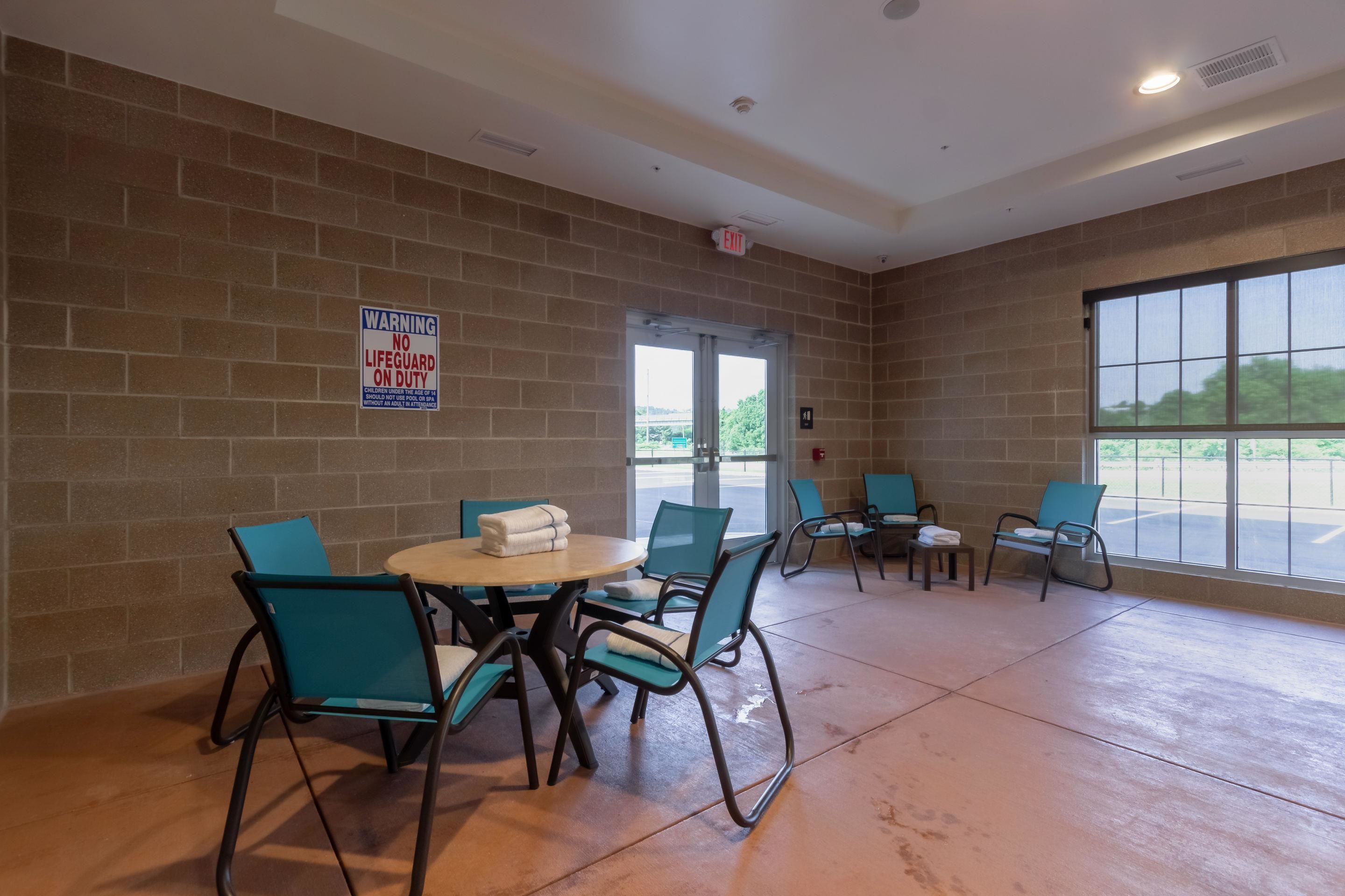 A room with brick walls, a round table with chairs, and a large window.