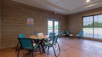 A room with brick walls, a round table with chairs, and a large window.