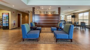 A lobby with blue seating, a vending machine, and a staircase. - Comfort Inn & Suites – Harrisburg Airport – Hershey South (Middletown)