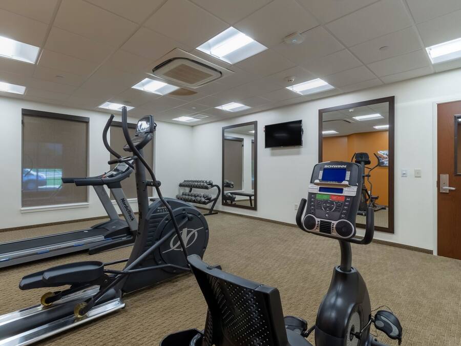 Un gimnasio con cintas de correr, elíptica y bicicleta estática.