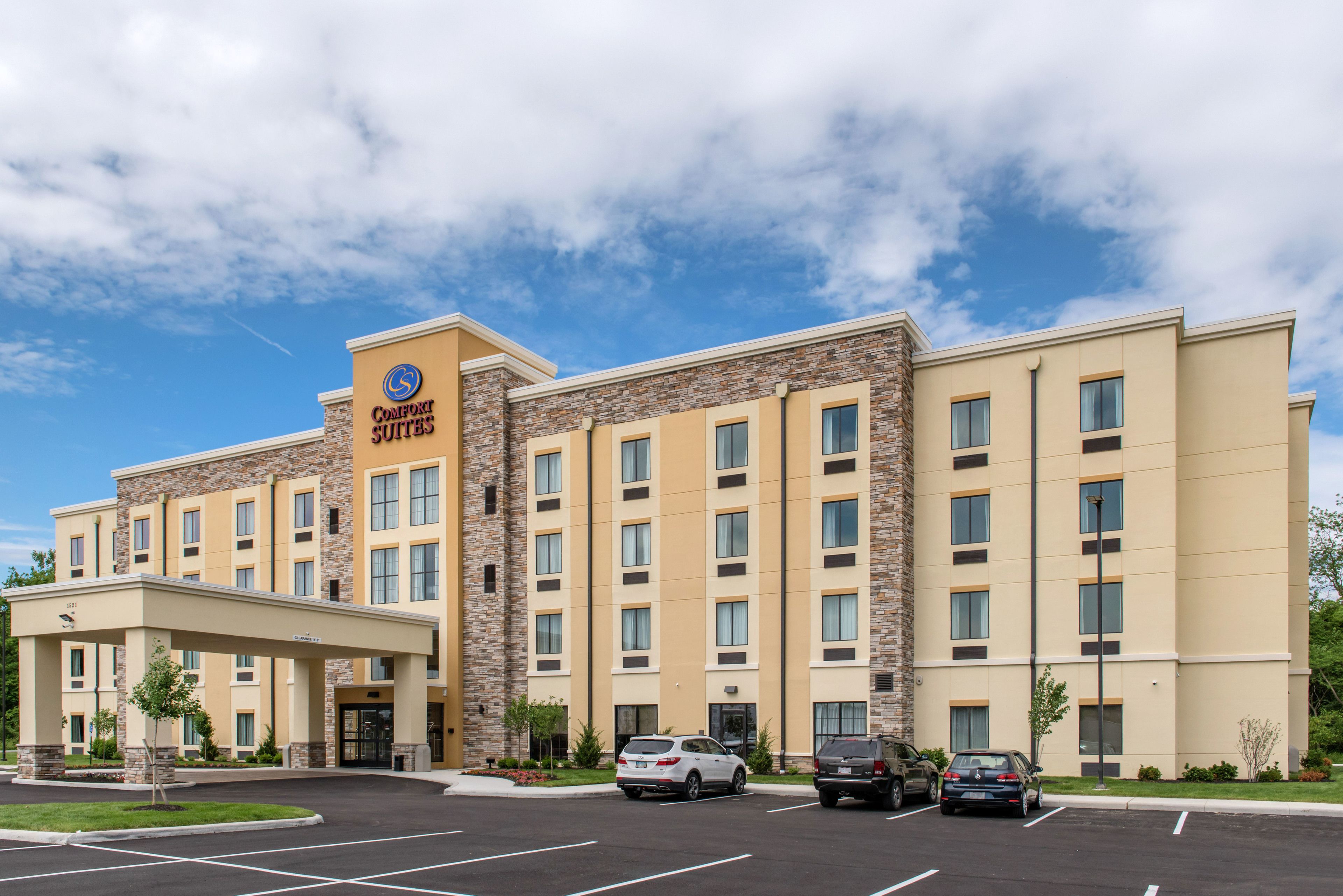 A hotel with a stone facade, multiple floors, and a parking lot.