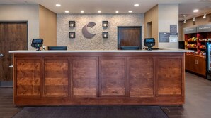 A reception desk with a wooden finish, a stone accent wall, and a large 'C' logo.