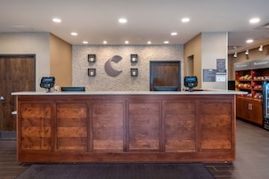 Mostrador de recepción con detalles de madera, pared decorativa de piedra y un gran logotipo 'C'.
