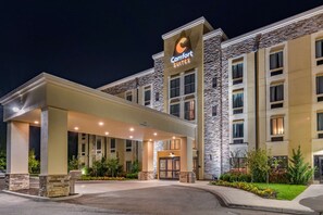 A hotel with a stone facade, a covered entrance, and a sign reading "Comfort Suites."