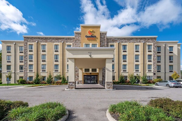 A Comfort Suites hotel with a stone facade, multiple floors, and a clear blue sky.