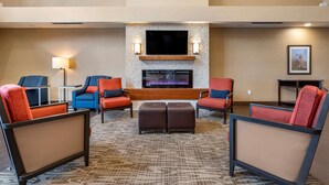 A hotel lobby with a fireplace, seating area, and a flat-screen TV.