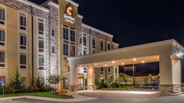 A Comfort Suites hotel with a stone facade, a covered entrance, and a parking area.