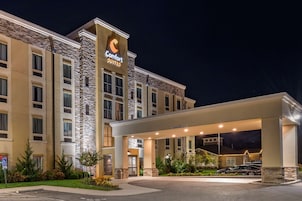 Un hotel Comfort Suites con fachada de piedra, un acceso cubierto y un estacionamiento.
