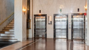 A spacious lobby with marble floors, a grand chandelier, and two elevators. - DoubleTree by Hilton Youngstown Downtown (Youngstown)