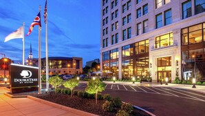 A hotel entrance with a sign reading "DOUBLETREE BY HILTON," a parking lot, and a building with multiple windows and a large entrance. - DoubleTree by Hilton Youngstown Downtown (Youngstown)