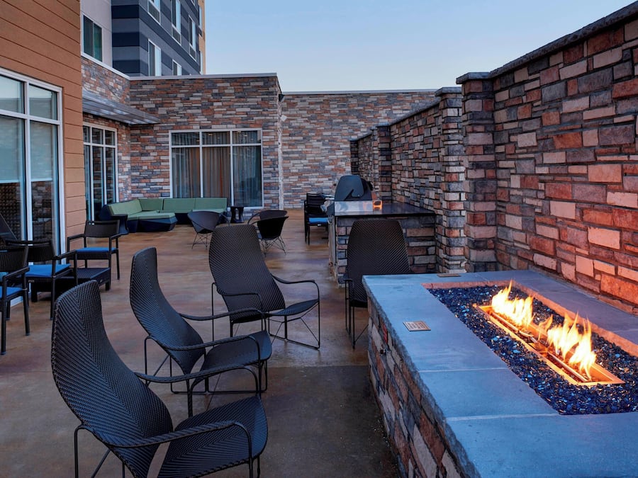 An outdoor patio with a fire feature, seating, and a barbecue grill.