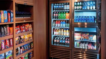 Máquina de vendas com diversos lanches e bebidas, incluindo batatas fritas, refrigerantes e água engarrafada.