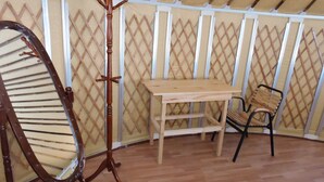 Ein Zimmer mit einem Holztisch, einem Stuhl und einem Kleiderständer.