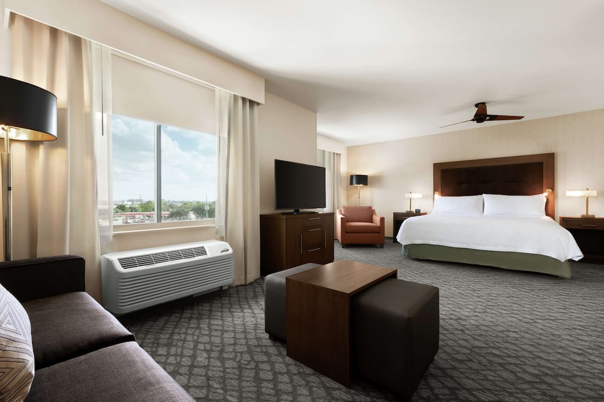 Habitación de hotel con una cama grande, televisión, escritorio, silla y vistas a la ciudad.
