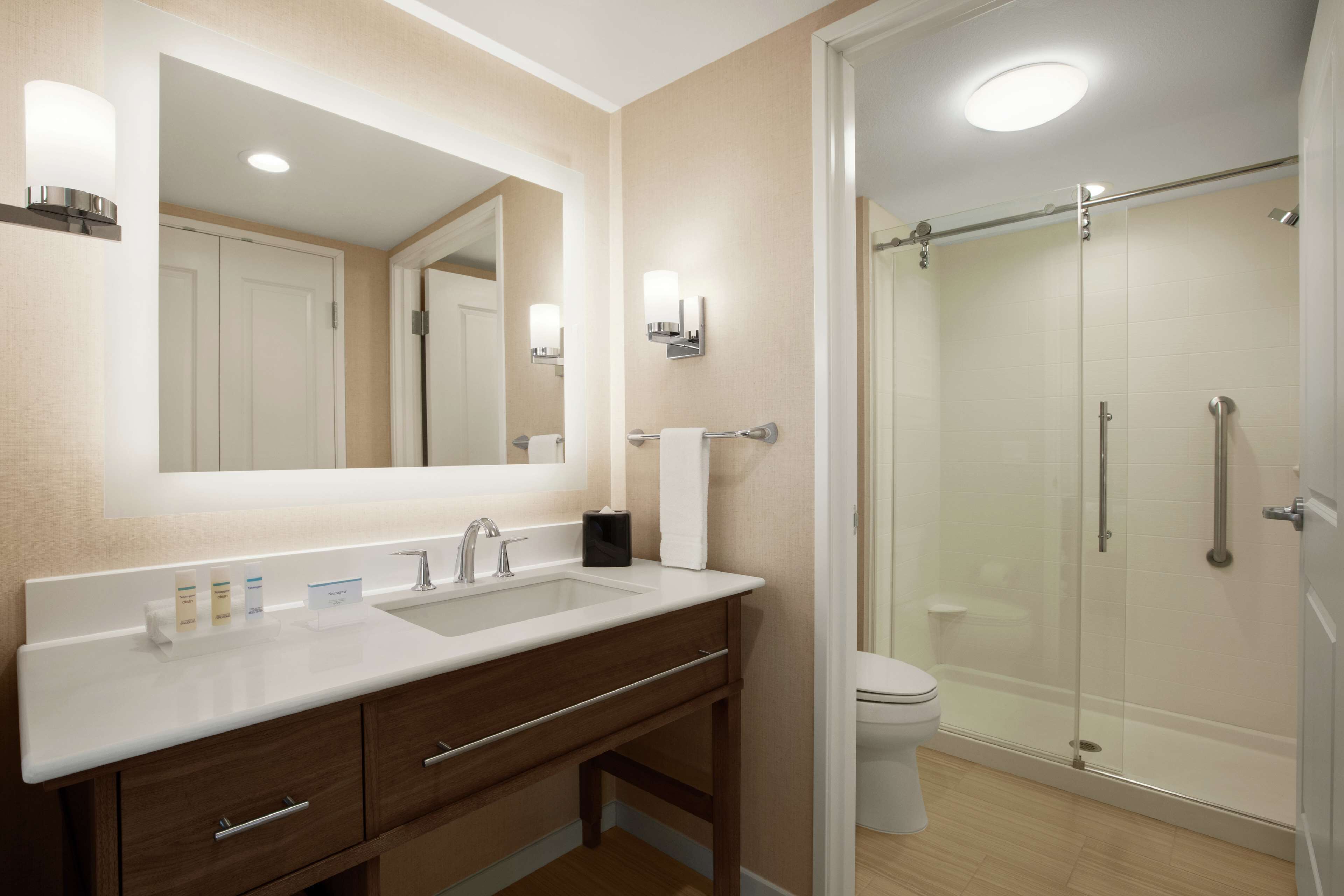 Une salle de bain moderne avec un grand miroir, deux lavabos, des toilettes et une douche à parois de verre.