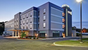 A multi-story hotel with a modern design, featuring a covered entrance and a well-lit facade. - Home2 Suites by Hilton Walpole Foxboro (Walpole)