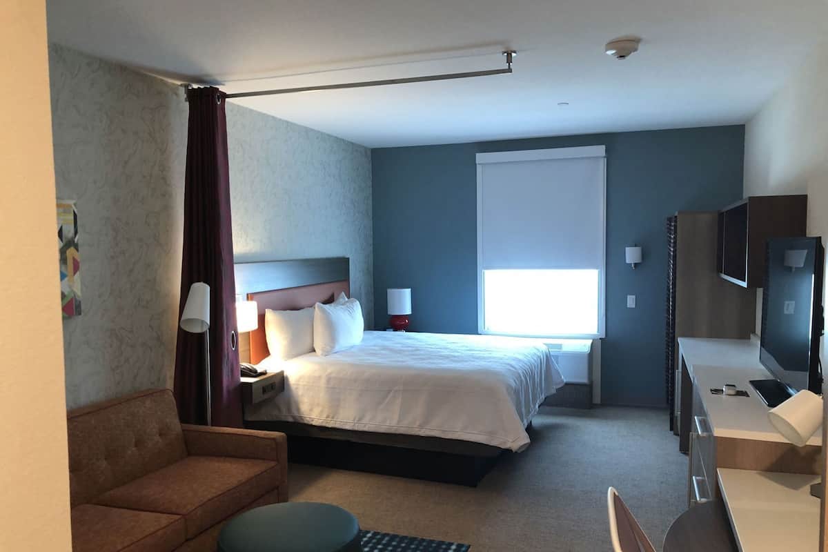 Hotelkamer met een bed, bureau, stoel, bank, televisie en raam.