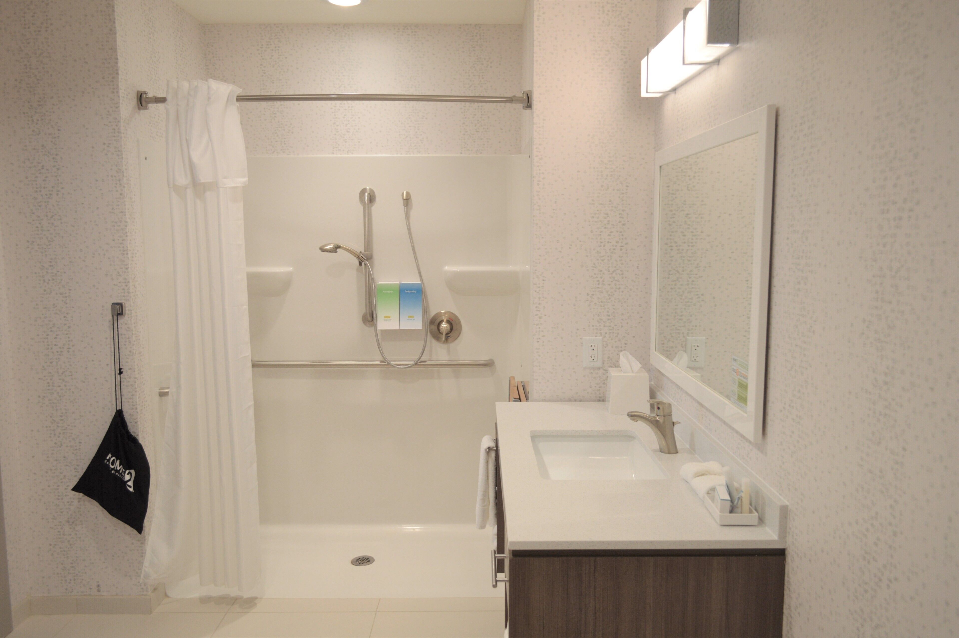 Un baño moderno con ducha, lavamanos y espejo.