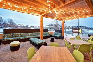 Un espacio de estar al aire libre cubierto con sofás estampados y sillas verdes, una mesa de madera y un letrero que dice 'HOME SUITES BY NILITO'.