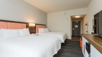 A hotel room with two beds, a wooden desk, and a mirror.