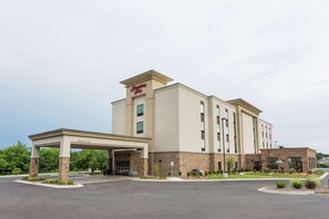 A Hampton Inn hotel with a covered entrance, a parking lot, and a landscaped area with plants. - Hampton Inn Cumberland (Cumberland)