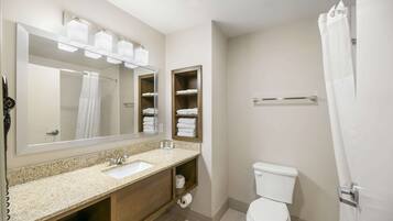 Un baño moderno con lavamanos de granito, un espejo grande y un inodoro.
